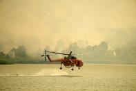 An helicopter fills water from Marathon Lake about 36 kilometres (22 miles) north of Athens, Greece, Friday, Aug. 6, 2021. Thousands of people fled wildfires burning out of control in Greece and Turkey on Friday, as a protracted heat wave turned forests into tinderboxes and flames threatened populated areas, electricity installations and historic sites. (AP Photo/Thanassis Stavrakis)