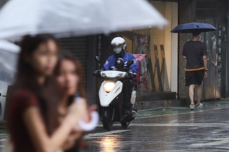 <cite>受颱風外圍環流影響，台北市1日下起間歇性陣雨，街道上民眾著雨衣撑傘擋雨勢。（柯承惠攝）</cite>