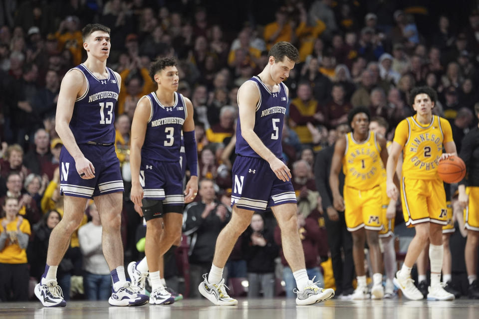 Northwestern guards Brooks Barnhizer (13), Ty Berry (3) and Ryan Langborg (5) walk off the court after an overtime loss to Minnesota in an NCAA college basketball game Saturday, Feb. 3, 2024, in Minneapolis. (AP Photo/Abbie Parr)