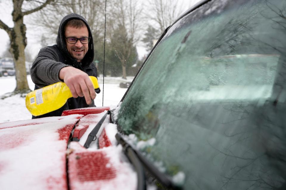 Brian Elsey, of Portland, Ore., cleans off his boss's car before heading home on Saturday, Jan. 13, 2024, in Portland. Brutally cold weather could prove a deadly challenge Saturday amid a continuing wave of Arctic storms that has hammered much of the country with blinding snow, freezing rain and whipping winds. (AP Photo/Jenny Kane) ORG XMIT: ORJK102