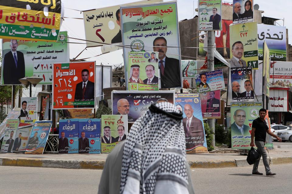 In this photo taken on April 15, 2014, Iraqis past election campaign posters in Basra, Iraq. The vibrant posters promise jobs, prosperity and security coming from Iraq’s first parliamentary elections since U.S. troops withdrew from the country, but so far, voters have only dim hopes as sectarian bloodshed rages unstopped. (AP Photo/Nabil al-Jurani)