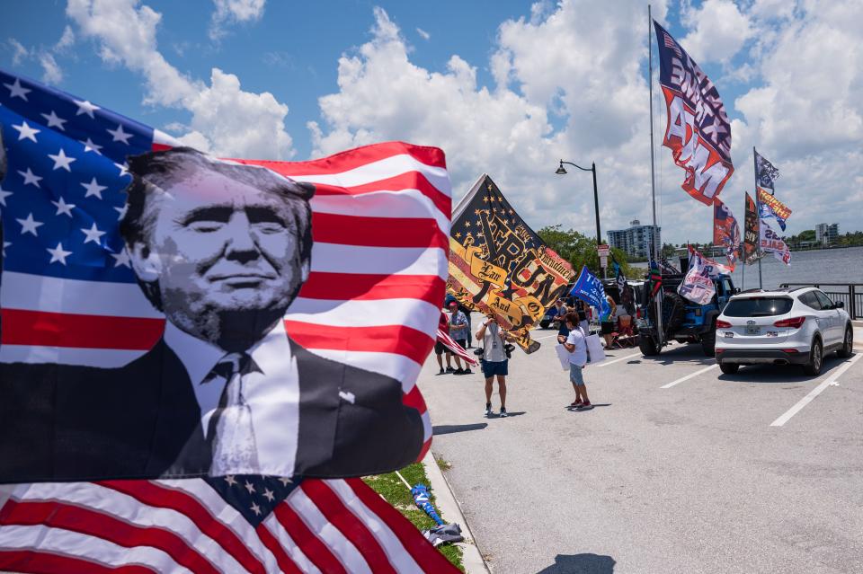 A group of supporters of the former President Donald Trump waves flags at passing traffic during a pro-Trump event on Sunday, June 11, 2023, on the bridge portion of Southern Boulevard in West Palm Beach, Fla.