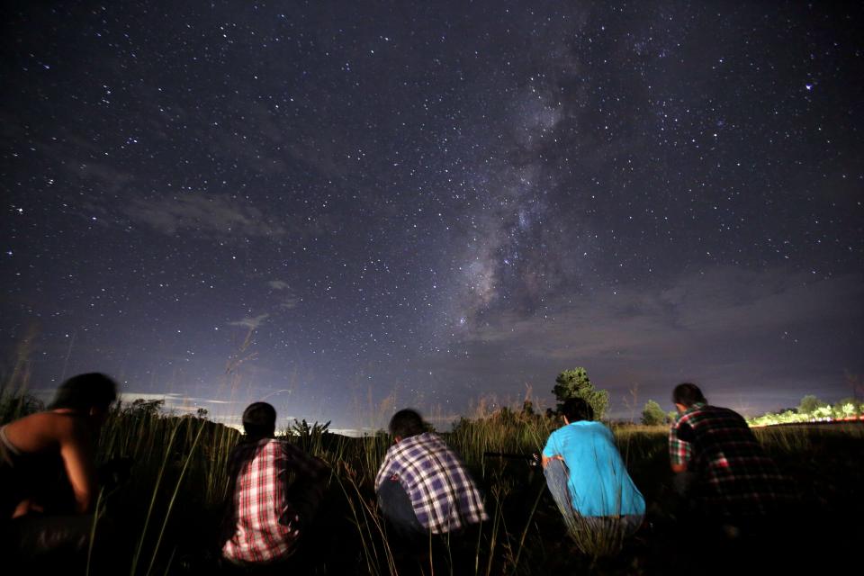 This long-exposure photograph taken on Aug. 12, 2013, shows people watching for the Perseid meteor shower in the night sky near Rangoon, Burma.