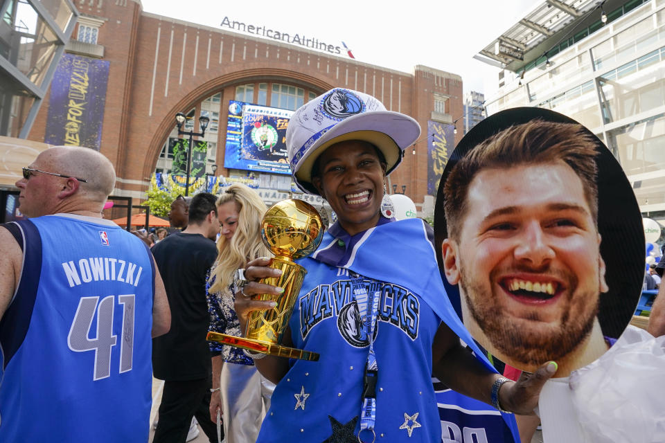 A spectator poses for a photograph with a poster donning the likeness of Dallas Mavericks guard Luka Doncic prior to Game 3 of the NBA basketball finals between the Mavericks and the Boston Celtics, Wednesday, June 12, 2024, in Dallas. (AP Photo/Sam Hodde)