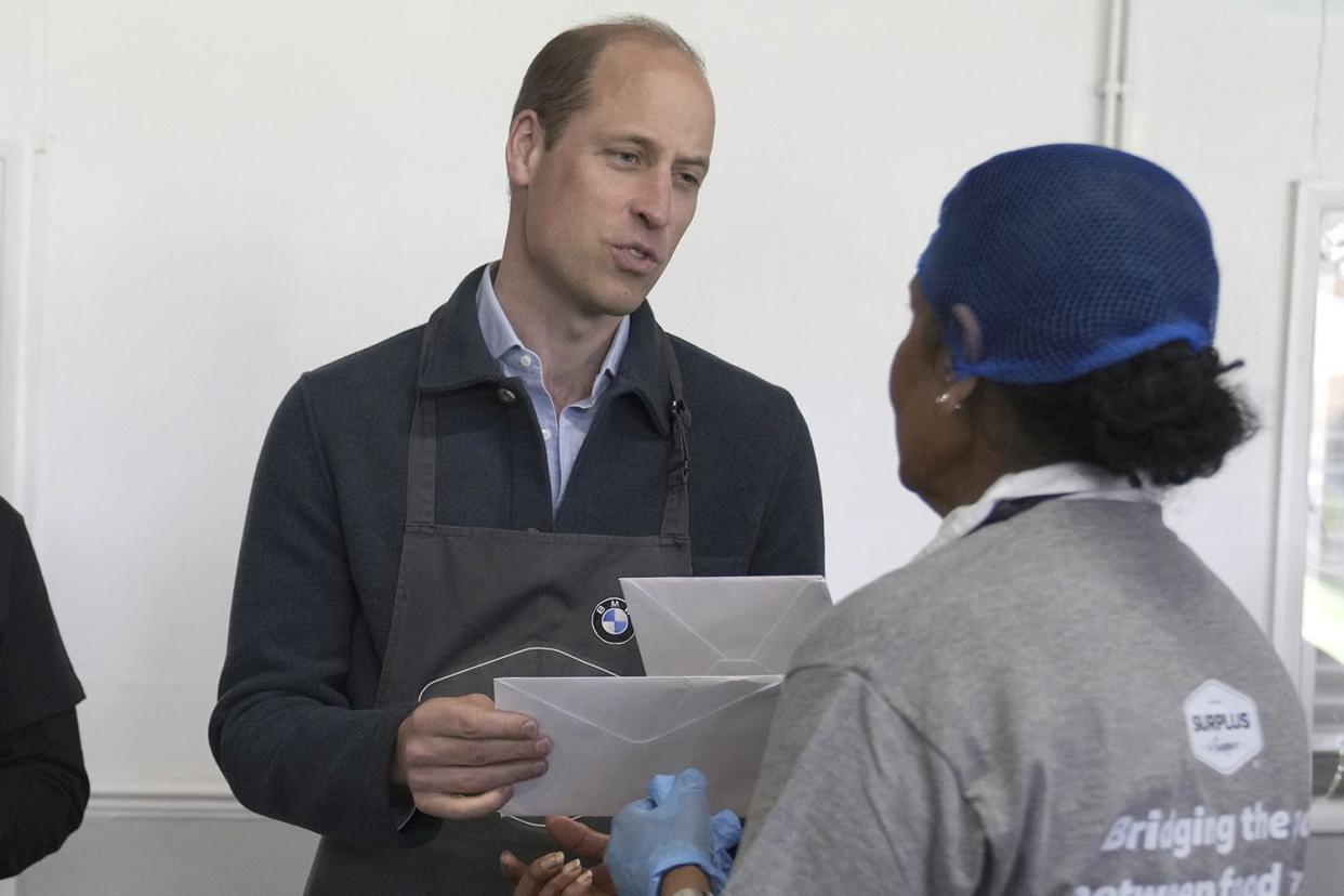 <p>Press Association via AP Images</p> Prince William accepts cards from volunteer Rachel Candappa during a visit to Surplus to Supper in Sunbury-on-Thames, Surrey, on April 18, 2024