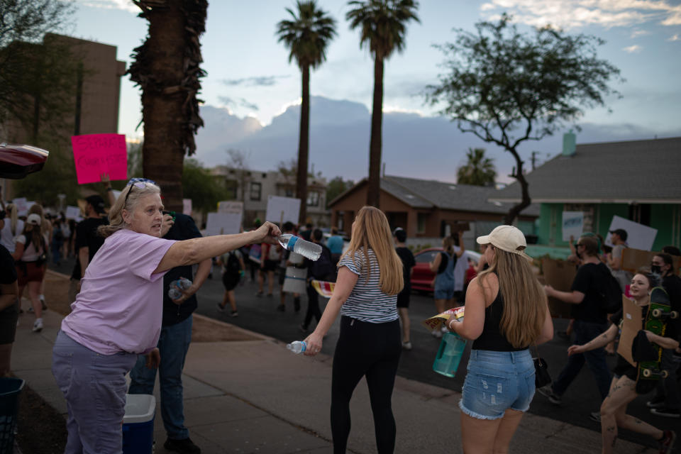 A middle-aged woman holds out a bottle of water to young protesters in Phoenix. 