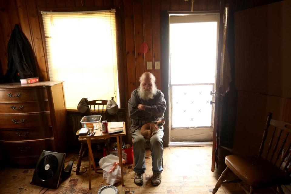 A man and his dog huddle in a dank room.