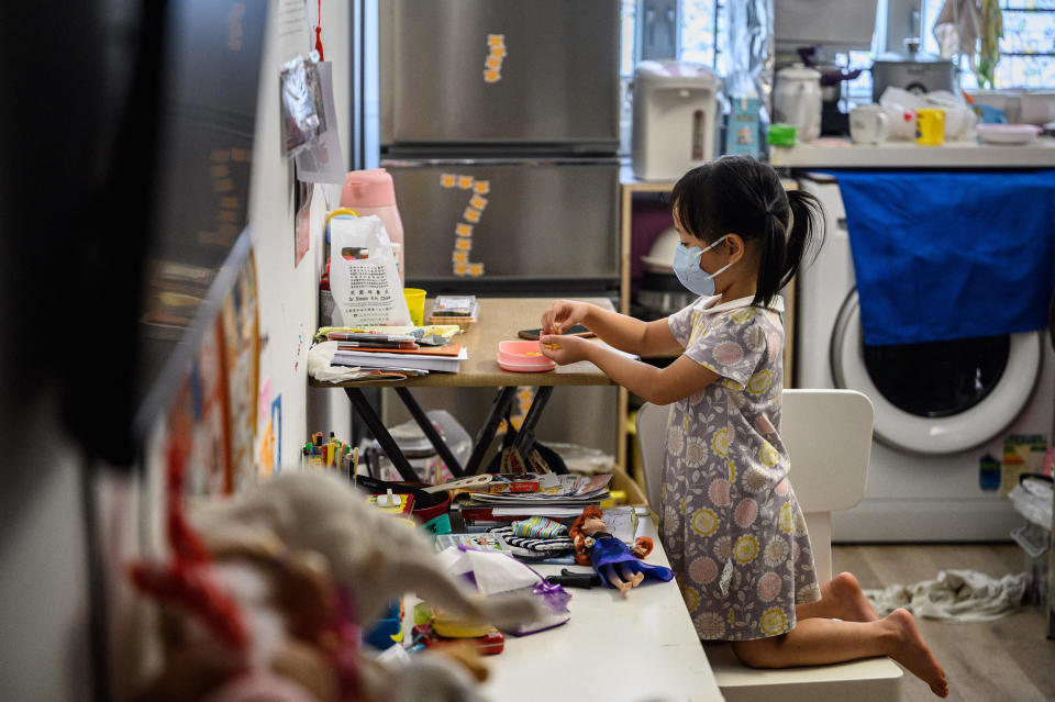 Image: A child eats a snack in her temporary 290 square-foot studio flat in Hong Kong. (Anthony Wallace / AFP via Getty Images)
