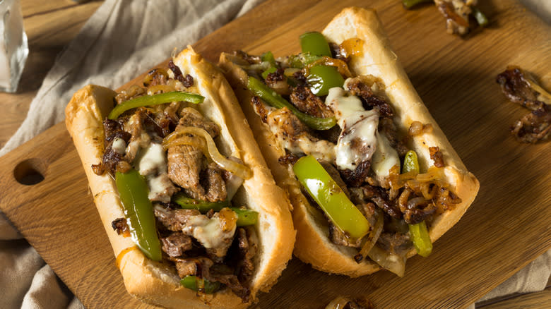Two Philly cheesesteaks on cutting board