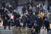 Travelers wear face masks as they walk outside the Beijing Railway Station in Beijing, Saturday, Feb. 15, 2020. People returning to Beijing will now have to isolate themselves either at home or in a concentrated area for medical observation, said a notice from the Chinese capital's prevention and control work group published by state media late Friday. (AP Photo/Mark Schiefelbein)