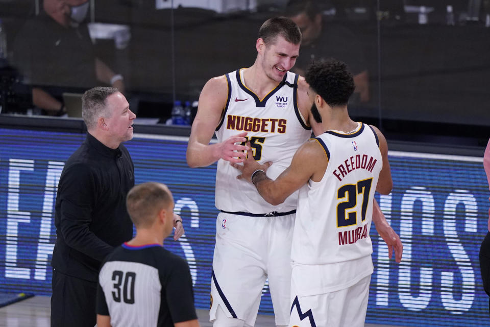 Denver Nuggets head coach Michael Malone, left, celebrates the team's win over the Los Angeles Clippers with center Nikola Jokic (15) and guard Jamal Murray (27) in an NBA conference semifinal playoff basketball game Tuesday, Sept. 15, 2020, in Lake Buena Vista, Fla. (AP Photo/Mark J. Terrill)