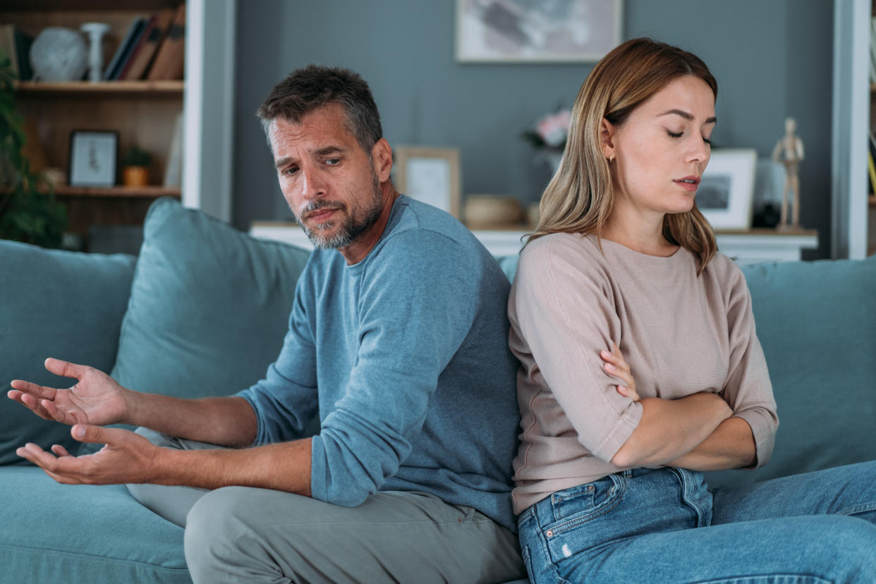 Shot of a young couple having a disagreement at home. Couple ignoring each other while sitting back to back on the couch. Man and woman with relationship problems sitting on sofa and not talking to each other.