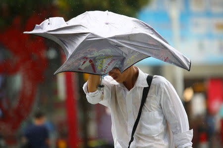 A man holds an umbrella against winds brought by Typhoon Hato in Foshan, Guangdong province, China August 23, 2017. REUTERS/Stringer