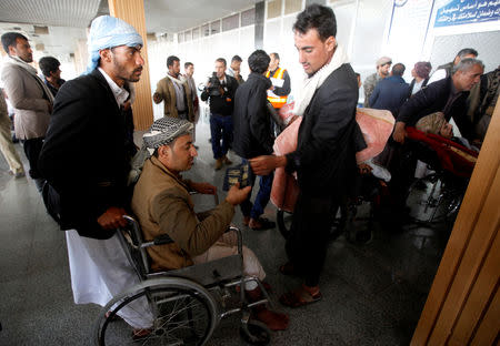 A wounded Houthi fighter, on a wheelchair, holds his passport at Sanaa airport during his evacuation from Yemen, December 3, 2018. REUTERS/Mohamed al-Sayaghi