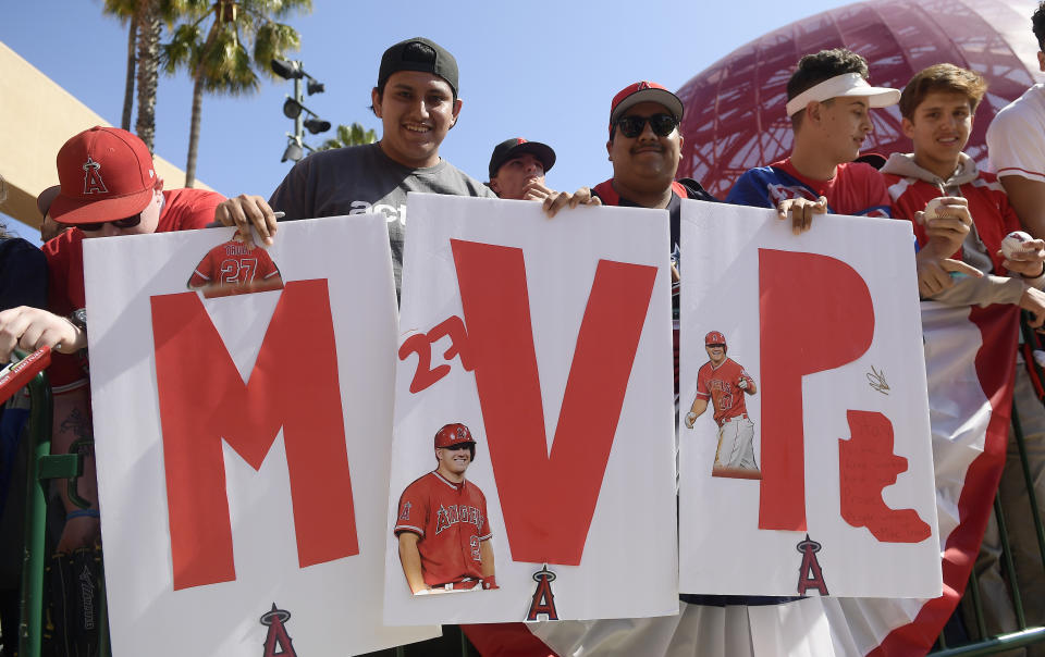 Fans hold up signs during during a news conference aboiut Los Angeles Angels center fielder Mike Trout's 12-year, $426.5 million contract, prior to the team's exhibition baseball game against the Los Angeles Dodgers on Sunday, March 24, 2019, in Anaheim, Calif. (AP Photo/Mark J. Terrill)