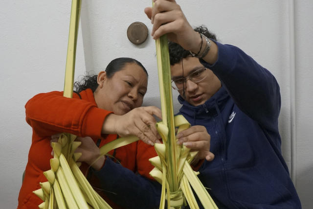 Elizabeth Ramirez and her son, Victor, learn how to weave palm fronds into traditional Mexican designs popular for Palm Sunday at the Church of the Incarnation in Minneapolis on Wednesday, March 29, 2023. The family attended a workshop in the church’s basement to prepare the palms, which will be sold at weekend services to raise funds for the historic church and will be blessed during the celebrations that start Holy Week. (AP Photo/Giovanna Dell’Orto)