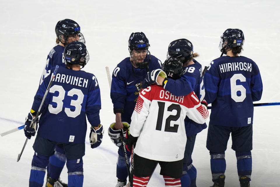 Japan's Chiho Osawa (12) is embraced by Finland's Ronja Savolainen (88) after a women's quarterfinal hockey game at the 2022 Winter Olympics, Saturday, Feb. 12, 2022, in Beijing. (AP Photo/Petr David Josek)