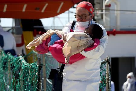 A doctor carries a child as migrants disembark from the Medecins Sans Frontieres (MSF) vessel at Pozzallo's harbour in Sicily, Italy, April 25, 2016. REUTERS/Antonio Parrinello