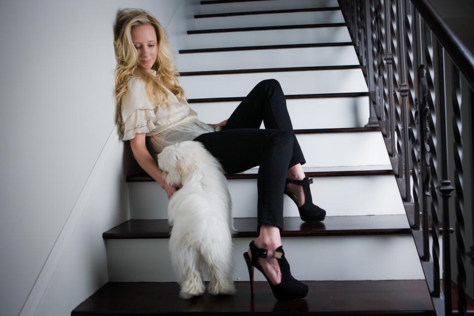 A woman sitting on a staircase pets a wet dog