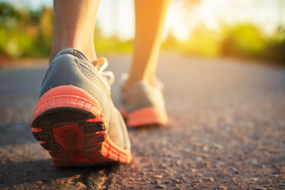 Close-up of a person’s legs in running shoes walking on a road. The focus is on the sole of the shoe