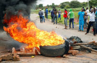 Protesters stand behind a burning barricade during protests on a road leading to Harare, Zimbabwe, January 15, 2019. REUTERS/Philimon Bulawayo/Files