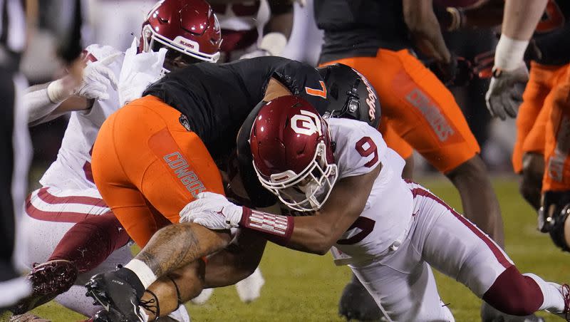 Oklahoma State running back Jaylen Warren is tackled by Oklahoma defensive lineman Isaiah Thomas (95) and cornerback D.J. Graham (9) during a game in 2021. Graham is one of 13 players from FBS programs who transferred to Utah State in the offseason.