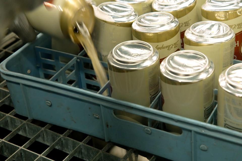 A worker at the Westlandia plant in Ypres, Belgium, pours out the contents of cans of Miller High Life beer prior to them being crushed on April 17, 2023. Belgian customs destroyed more than 2,000 cans of the beer, which is advertised as "The Champagne of Beers” at the request of houses and growers of the bubbly beverage.