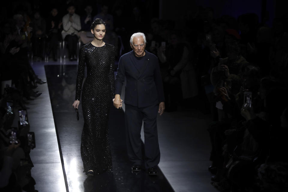 Designer Giorgio Armani, right, accepts applause as he walks with a model after the Giorgio Armani women's Fall-Winter 2019-2020 collection, that was presented in Milan, Italy, Saturday, Feb. 23, 2019. (AP Photo/Luca Bruno)