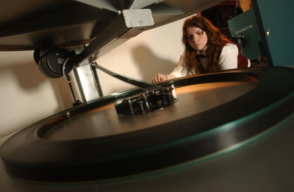 Carmike employee Christy King watches the film platter on one of the 35 millimeter projectors at Carmike Cinemas in Wilmington in 2006.