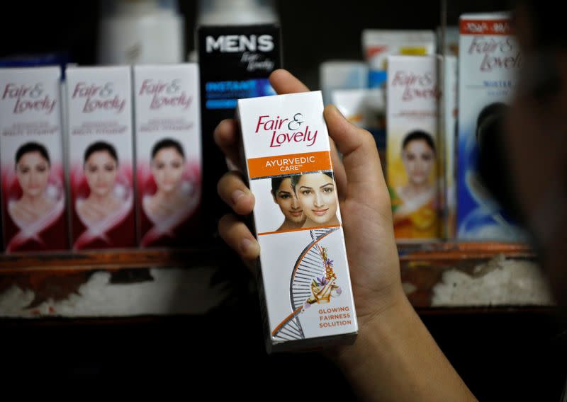 A customer picks up "Fair & Lovely" brand of skin lightening product from a shelf in a shop in Ahmedabad