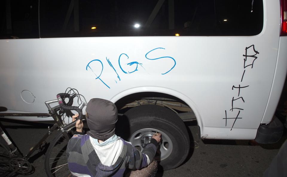 A protester lets air out of a police vehicle's tire during a protest against police violence in the U.S., in Berkeley, California