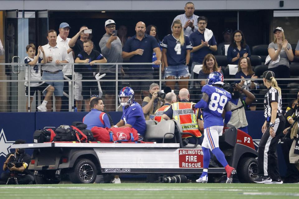 Fans look on as New York Giants wide receiver Kadarius Toney (89) jogs over to talk with quarterback Daniel Jones who is carted off the field after suffering an unknown injury in the first half of an NFL football game against the Dallas Cowboys in Arlington, Texas, Sunday, Oct. 10, 2021. (AP Photo/Ron Jenkins)