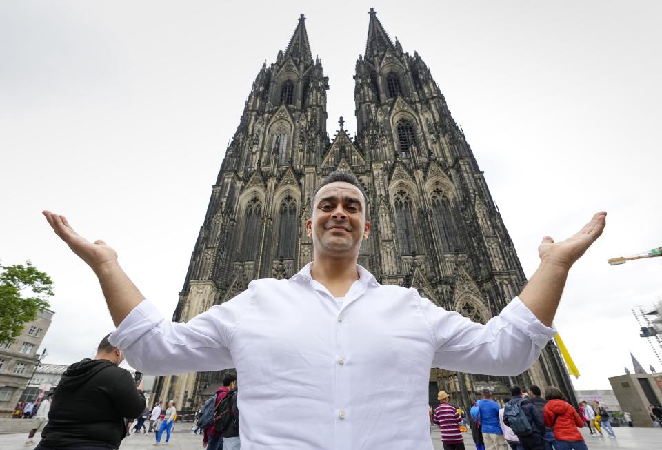 Fadel Alkhudr from Syria poses in front of the word heritage Cologne Cathedral in Cologne, Germany, Monday, June 20, 2022. Fadel Alkhudr, 42, a woodcarver and artist orginally from Aleppo, Syria, fled the war in his home country and arrived in the western german city of Cologne in 2015. In 2019 he started to carve the local Cologne Cathedral in his small basement - without any plans or drawings, using only cell phone photos of the cathedral as a template. (AP Photo/Martin Meissner)