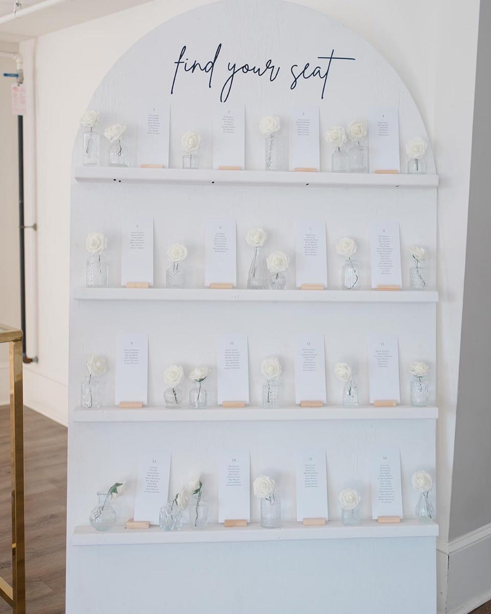 A rounded sign that says "find your seat" with flowers and cards on it.