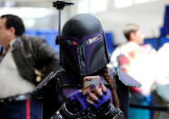 An attendee keeps tabs on her cell phone as she walks the convention floor at Comic-Con. REUTERS/Mike Blake