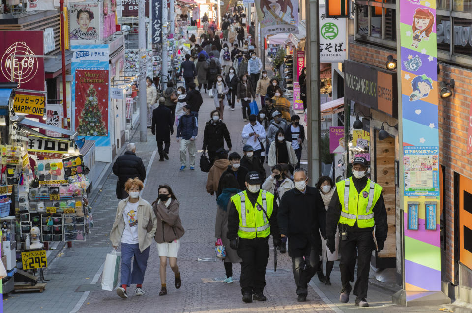 People wearing face masks walk through a famed shopping street in the Harajuku neighborhood in Tokyo on Thursday, Dec. 17, 2020. The Japanese capital confirmed more than 800 new coronavirus cases on Thursday. (AP Photo/Hiro Komae)