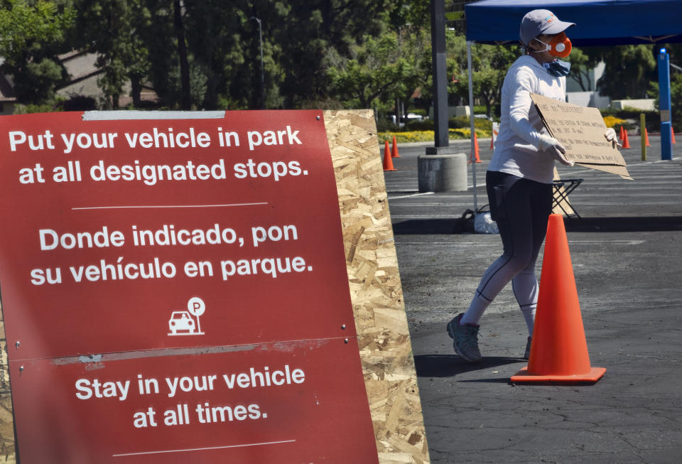 A CORE (Community Organized Relief Effort) volunteer checks for appointments and directing cars that lined up for coronavirus testing in the Woodland Hills section of Los Angeles. The city of Los Angeles is providing free coronavirus tests to anyone who wants one regardless of whether they have symptoms. The offer reflects a parting with state guidelines after the mayor partnered with a startup testing company. The test the city is offering is easier to administer and doesn't require the scarce supplies that have created bottlenecks for expanded testing across California. (AP Photo/Richard Vogel,File)