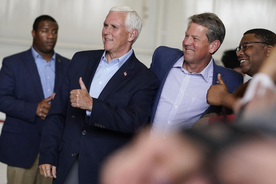 Former Vice President Mike Pence, second from left, and Georgia Gov. Brian Kemp, center, pose for a photo with a supporter after a Get Out the Vote Rally, on the eve of gubernatorial and other primaries in the state, on Monday, May 23, 2022, in Kennesaw, Ga. (AP Photo/Brynn Anderson)