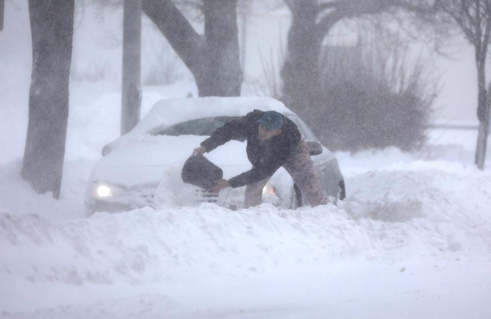 Eric Klein of Canandaigua tries to dig out his car on Franklin Street in Rochester, NY with a bucket, after the snow storm dumped at least a foot of snow overnight on Monday, January 17, 2022.   He said he was unprepared for the snow and had spent the night in Rochester.