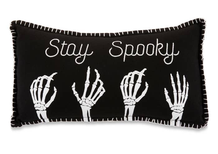 the black pillow with white lettering, stitching and skeleton hands