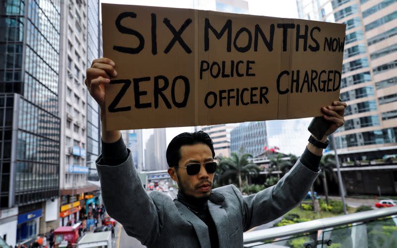 A man holds a placard as anti-government office workers attend a lunch time protest in Hong Kong