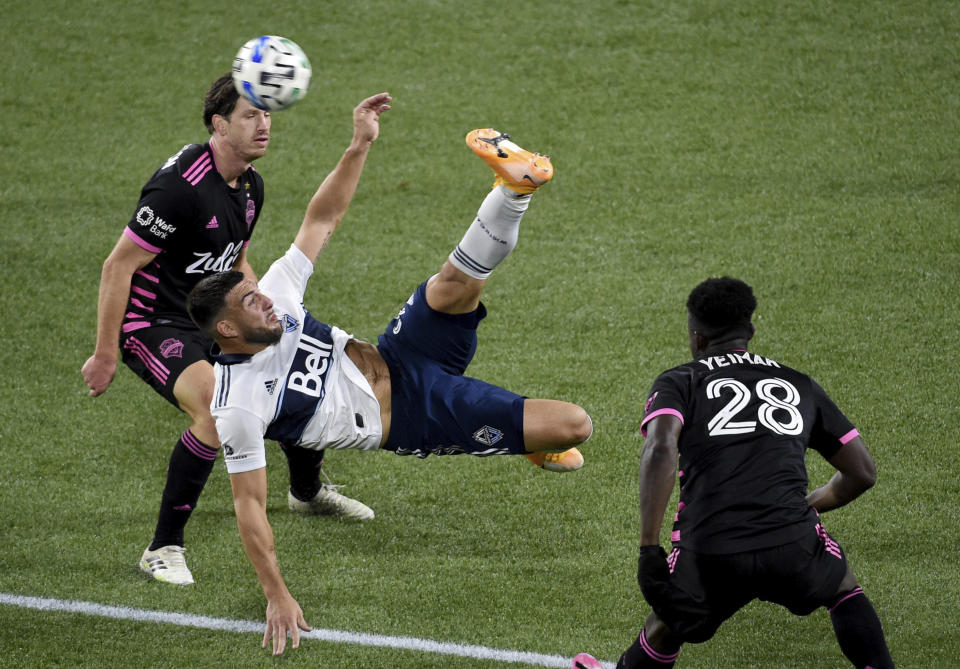 Vancouver Whitecaps forward Lucas Cavallini, center, does a bicycle kick in front of Seattle Sounders defender Yeimar Gomez, right during the second half of an MLS soccer match in Portland, Ore., Tuesday, Oct. 27, 2020. Seattle won 2-0. (AP Photo/Steve Dykes)