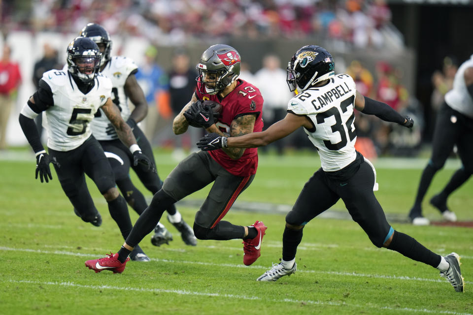 Tampa Bay Buccaneers wide receiver Mike Evans (13) runs past Jacksonville Jaguars cornerback Tyson Campbell (32) and safety Andre Cisco (5) after a reception during the first half of an NFL football game Sunday, Dec. 24, 2023, in Tampa, Fla. (AP Photo/Chris O'Meara)