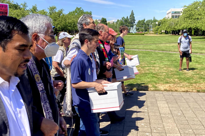 FILE - Backers of a proposed initiative that would require individuals to secure permits to buy firearms and ban large-capacity magazines deliver the signatures of thousands of voters on Friday, July 8, 2022, to state election offices in Salem, Ore. Oregonians will vote Tuesday, Nov. 8, 2022, on a slate of measures including one that would add a permit and in-person firearms training class for new gun buyers and another that would make Oregon the first state to mandate health care as a human right. (AP Photo/Andrew Selsky, File)
