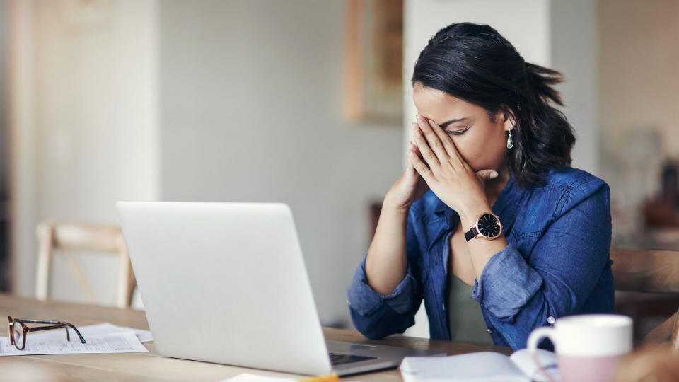 Shot of a young woman looking stressed while using a laptop to work from home.