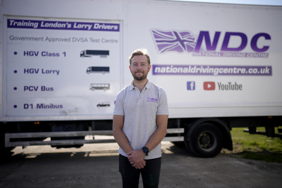 Laurence Bolton, the Managing Director of the National Driving Centre, poses for a portrait backdropped by a sign on the side of a truck showing different truck and vehicle categories, at the National Driving Centre in Croydon, south London, Wednesday, Sept. 22, 2021. Britain doesn't have enough truck drivers. The shortage is contributing to scarcity of everything from McDonald's milkshakes to supermarket produce. (AP Photo/Matt Dunham)