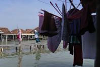 People walk through Timbulsloko, Central Java, Indonesia, Sunday, July 31, 2022. Some residents of the village have received aid from the local government, but many are still left without a dry place to sleep, afraid a strong tide in the middle of the night could wash them out to sea. (AP Photo/Dita Alangkara)