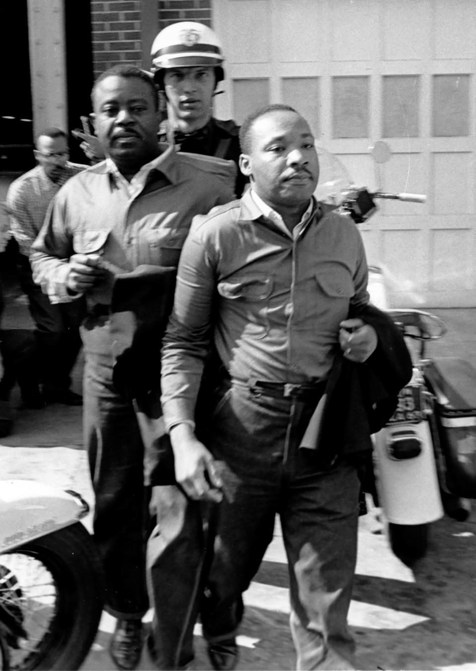 The Rev. Ralph Abernathy, left, and the Rev. Martin Luther King Jr., right are taken by a police officer as they lead a line of demonstrators into the business section of Birmingham, Ala., on April 12, 1963.