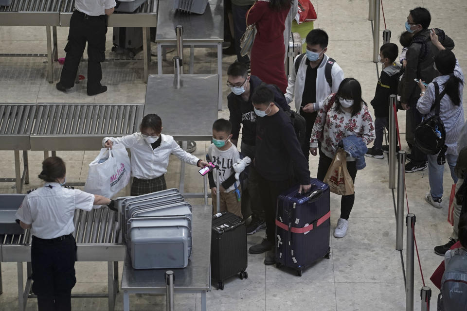 Passengers cross the security check at the departure hall of the high speed train station in Hong Kong, Thursday, Jan. 23, 2020. China closed off a city of more than 11 million people Thursday, halting transportation and warning against public gatherings, to try to stop the spread of a deadly new virus that has sickened hundreds and spread to other cities and countries in the Lunar New Year travel rush. (AP Photo/Kin Cheung)