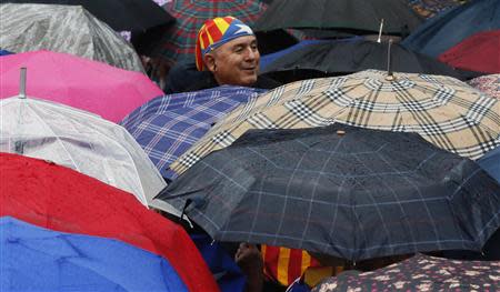 A man peers between umbrellas as he wears a bandana depicting an "Estelada" (Catalonia separatist flag) flag during a ceremony to mark the "Diada de Catalunya" (Catalunya's National day) in central Barcelona September 11, 2013. REUTERS/Gustau Nacarino